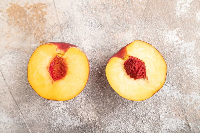Peach Cut in half on brown concrete background. Top view, flat lay, close up. healthy food, vegetable, minimalism