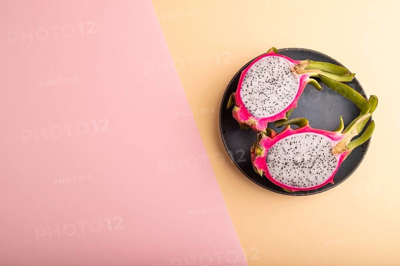 Ripe Pitaya on blue plate on pink and orange pastel paper background, top view, flat lay, copy space, minimalism