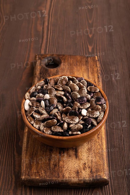 Wooden bowl with Kidney beans on brown wooden background, side view, copy space, minimalism