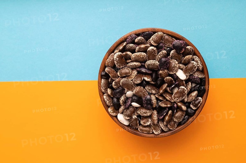 Wooden bowl with Kidney beans on blue and orange pastel paper background, top view, flat lay, copy space, minimalism