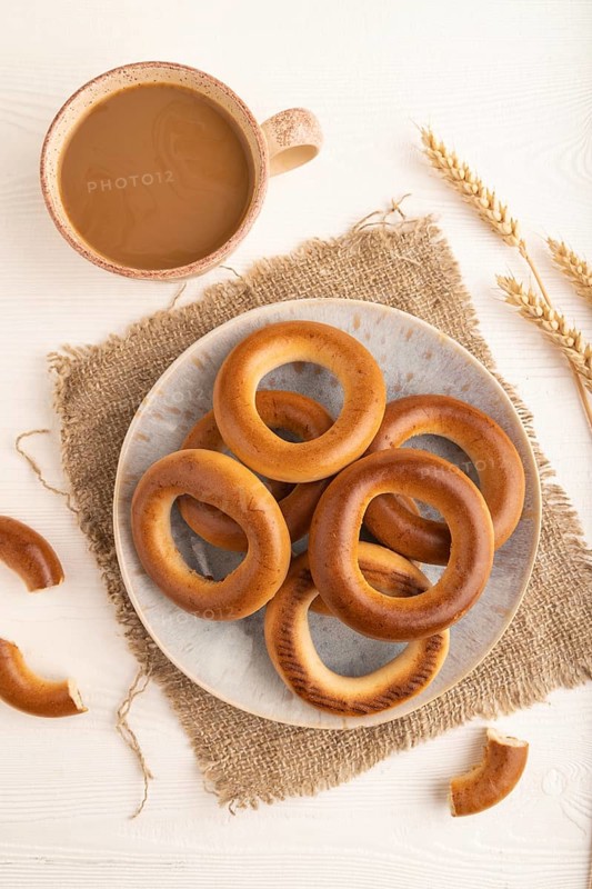 Homemade Ring Bagel with cup of coffee on white wooden background and linen textile. top view, flat lay, close up