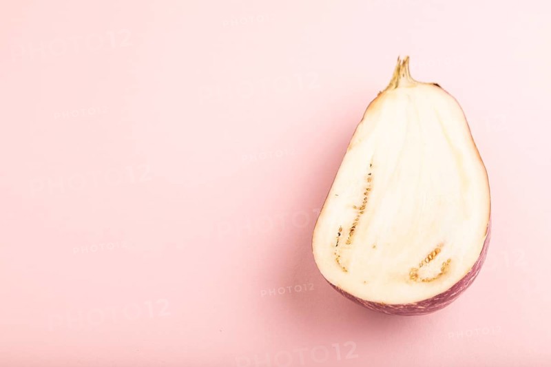 Purple Cutted eggplant with white stripes on pink pastel background. Side view, copy space. Tropical, healthy food, vegetable, slice, minimalism