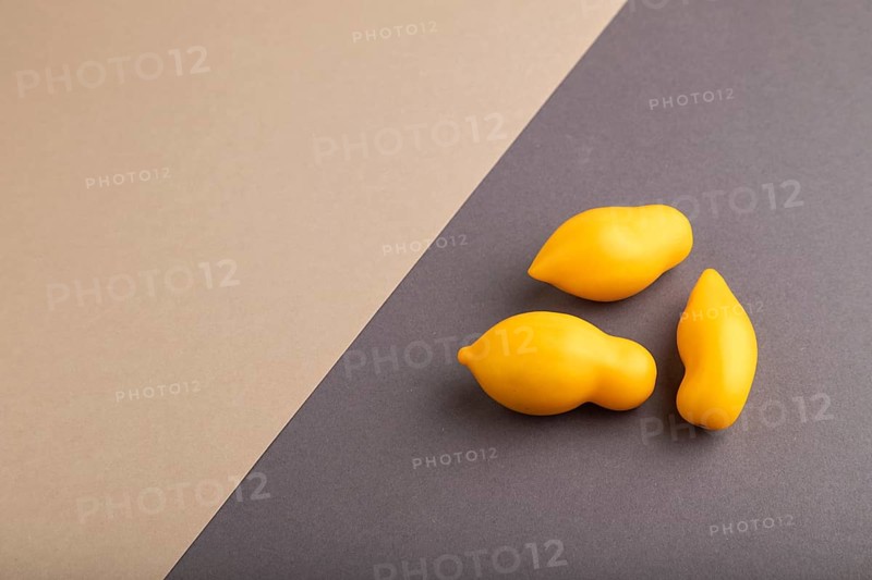 Yellow tomatoes on beige and gray pastel paper background. Side view, copy space. healthy food, vegetable, minimalism