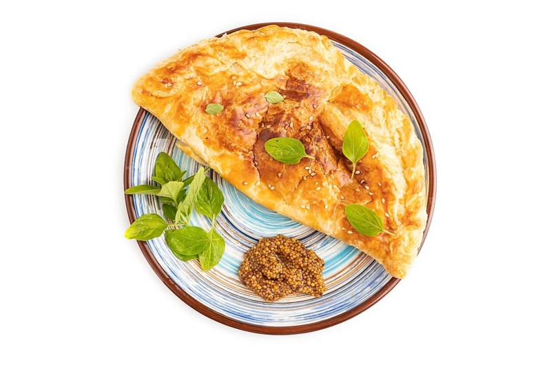 Fried homemade Khachapuri cake with cheese and meat, fried in pan. Traditional Georgian cuisine isolated on white background. Top view, flat lay, close up
