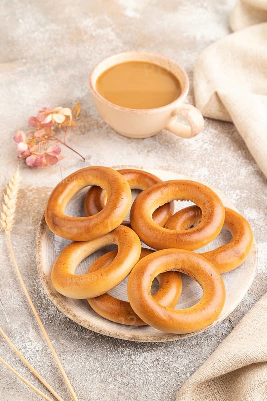 Homemade Ring Bagel with cup of coffee on brown concrete background and linen textile. side view, close up