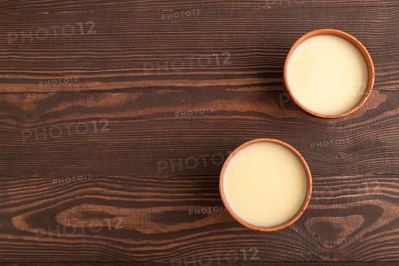 Organic non dairy banana and soy milk in clay cup on brown wooden background. Vegan healthy food concept, flat lay, top view, copy space
