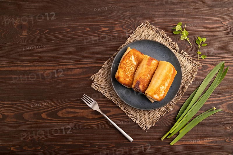 Fried crispy pancakes with meat and cheese on brown wooden background and linen textile. top view, flat lay, copy space