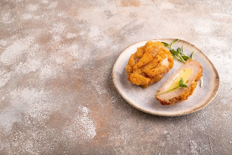 Chicken schnitzel on blue plate with microgreen on brown concrete. Diet, healthy eating. side view, copy space