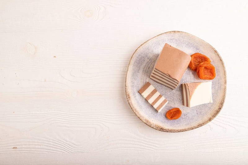 Cocoa and milk jelly with dried apricots on white wooden background, top view, flat lay, copy space, minimalism