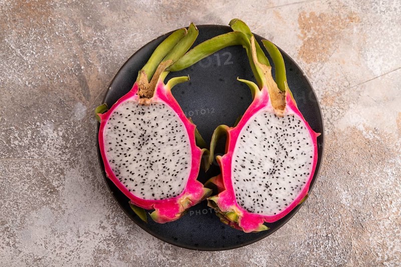 Ripe Pitaya on blue plate on brown concrete background, top view, flat lay, copy space, minimalism