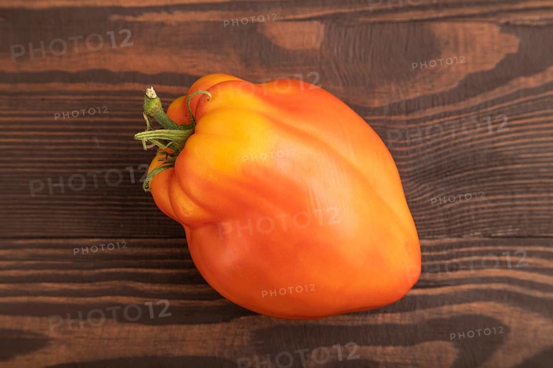 Red Heart Shape tomato on brown wooden background. Top view, flat lay, close up. healthy food, vegetable, minimalism