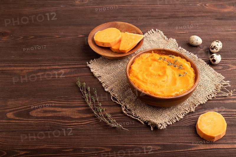 Sweet potato porridge in wooden bowl on wooden background and linen textile. Diet, healthy eating concept. side view, copy space, minimalism