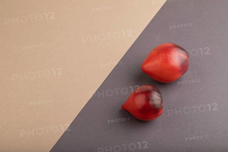 Red Heart shape tomatoes on gray and beige pastel paper background. Side view, copy space. healthy food, vegetable, minimalism