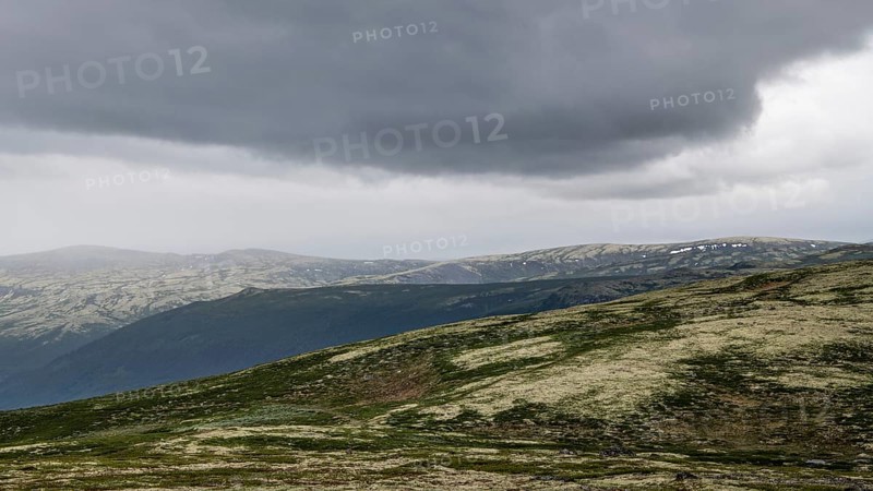Vast mountain landscape with patches of snow and a cloudy atmosphere, pilgrimage route Olavsweg or Olavsleden, old Kongevegen or King's Path over Dovrefjell, Norway