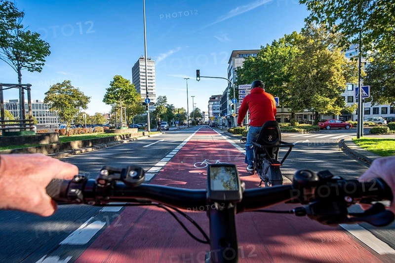 Riding a bike in a bike lane, marked in red to attract the attention of motorists, between 2 lanes, Huyssenallee, in front of Europaplatz, in the city centre of Essen, North Rhine-Westphalia, Germany