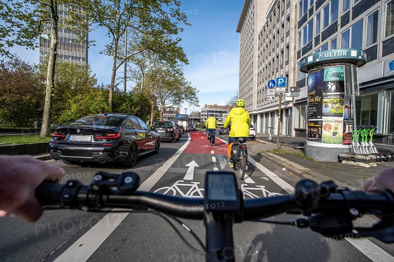 Riding a bike in a bike lane, marked in red to attract the attention of motorists, between 2 lanes, Huyssenallee, in front of Europaplatz, in the city centre of Essen, North Rhine-Westphalia, Germany