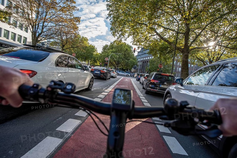 Riding a bike in a bike lane, marked in red to make drivers aware of the bike lane, between 2 lanes, Huyssenallee, in the city centre of Essen, North Rhine-Westphalia, Germany