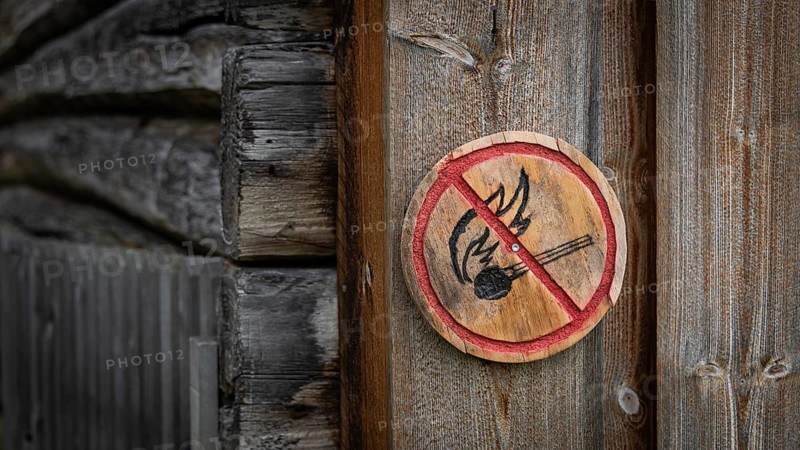 Runde Holztafel mit aufgemaltem Verbotssymbol gegen das Entfachen von Feuer, historischer Bauernhof und Pilgerunterkunft Budsjord, Dovre, Pilgerweg Olavsweg oder Olavsleden, Gudbrandsdalen oder Gudbrandstal, Norwegen