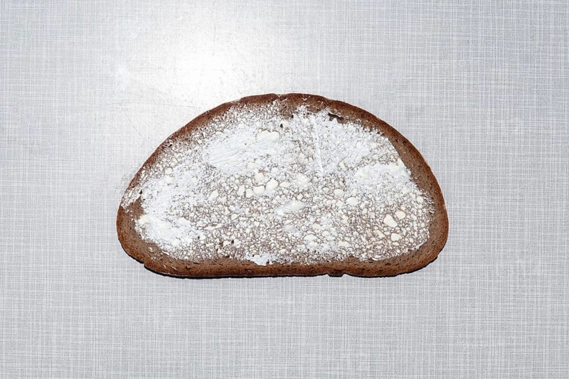 Top shot of a slice of bread smeared with margarine on a white Resopal plate