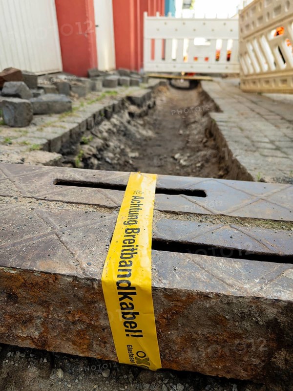 Flapping tape with the indication of an installed fibre optic cable at a construction site in Wuppertal, Germany