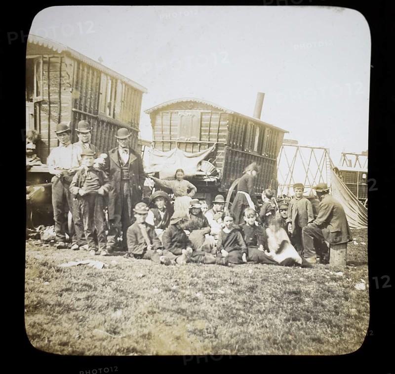 Magic lantern slide portrait of fairground travelling gypsy extended family and caravans, UK circa 1900