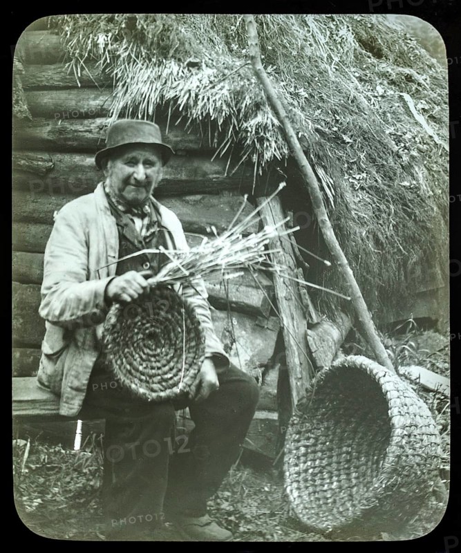 Portrait of elderly countryman weaving straw baskets in England, c 1890s-1900