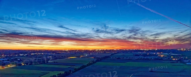 Panorama der Hamburger Vier- und Marschlande bei Nacht. Im Hintergrund die beleuchtete Silhouette der Stadt. Luftaufnahme. Hamburg, Deutschland