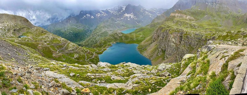Panoramic view of left serpentine narrow bends from ascent pass road to Alpine pass Colle del Col de Nivolet, right foreground mountain lake Lago Agnel, rear reservoir Lago Serru Serrù, Gran Paradiso National Park, Ceresole Reale, Piedmont, Italy