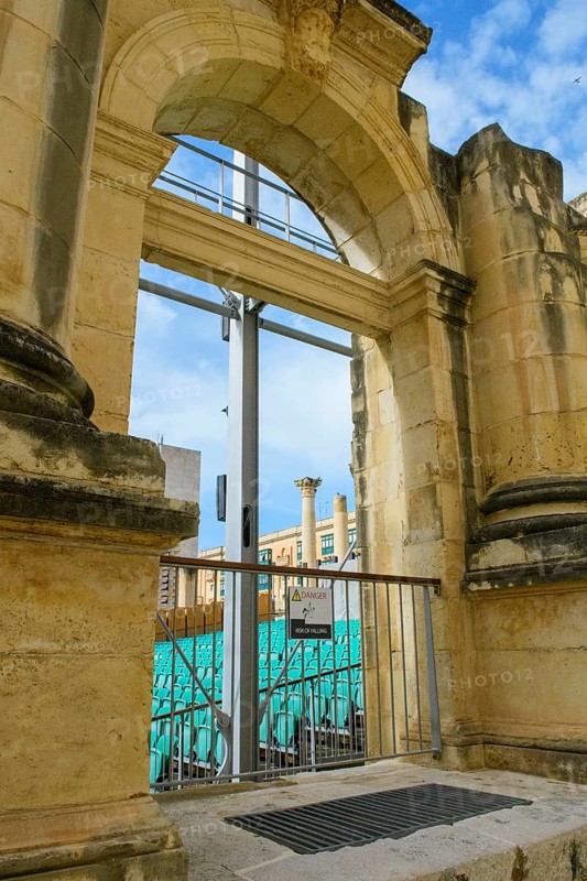 View through former arched window of ruins of former opera house Royal Opera House of Valletta destroyed in World War II on seating of integrated open-air stage, Valletta, Malta