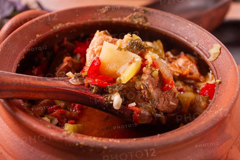 Chanakhi, a Georgian dish. in a clay pot, on a wooden table, stewed meat with vegetables, homemade, no people