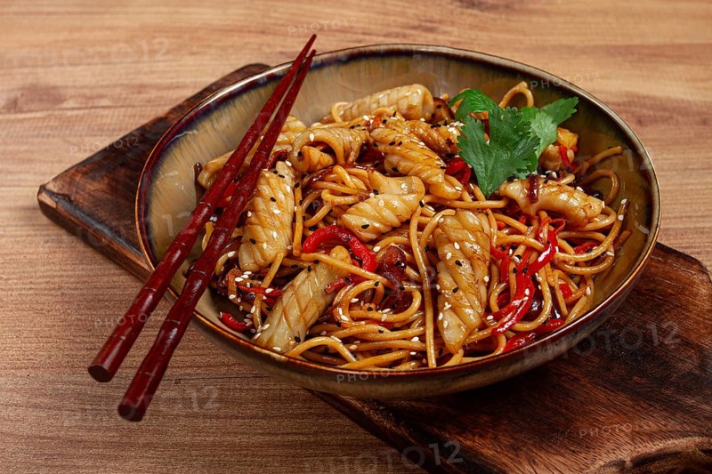 Udon noodles, with squid and vegetables, on a wooden table, homemade, no people