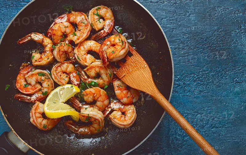 Fried tiger prawns, jumbo, in garlic sauce, in butter, with herbs, in a frying pan, homemade, no people