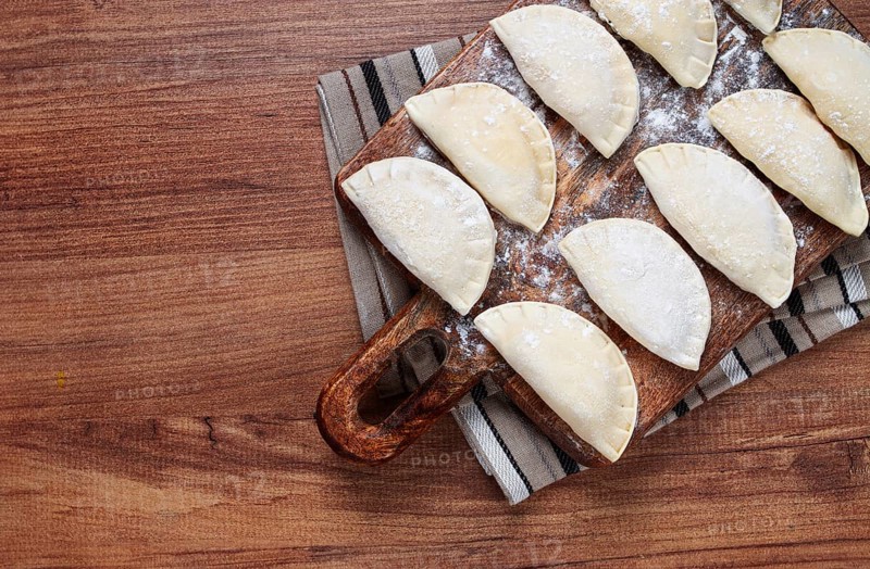 Traditional Polish dish, dumplings, raw, frozen, on a cutting board, wooden table, top view, no people