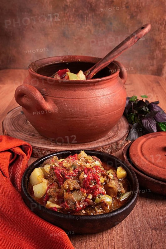 Chanakhi, a Georgian dish. in a clay pot, on a wooden table, stewed meat with vegetables, homemade, no people