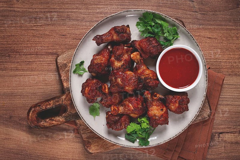 Juicy fried chicken pieces, served with spicy dipping sauce, on a rustic wooden table