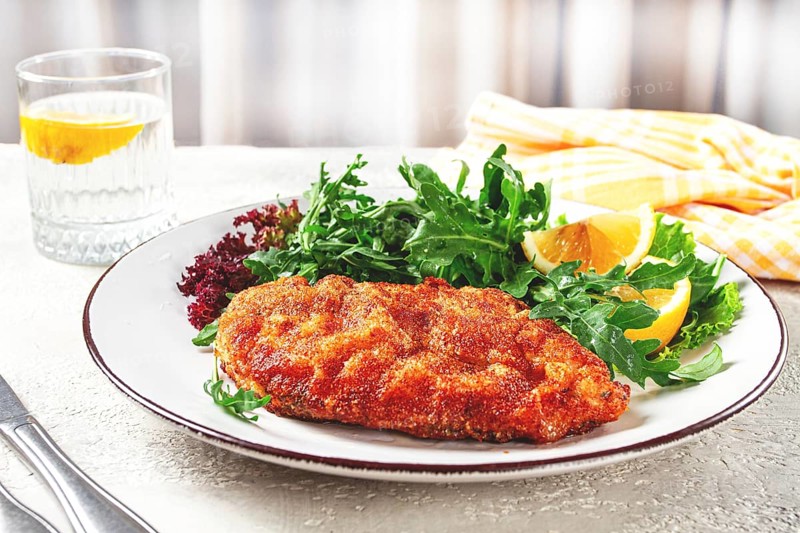 Milanese chicken, Crispy breaded chicken served, with fresh herbs, and lemon wedges