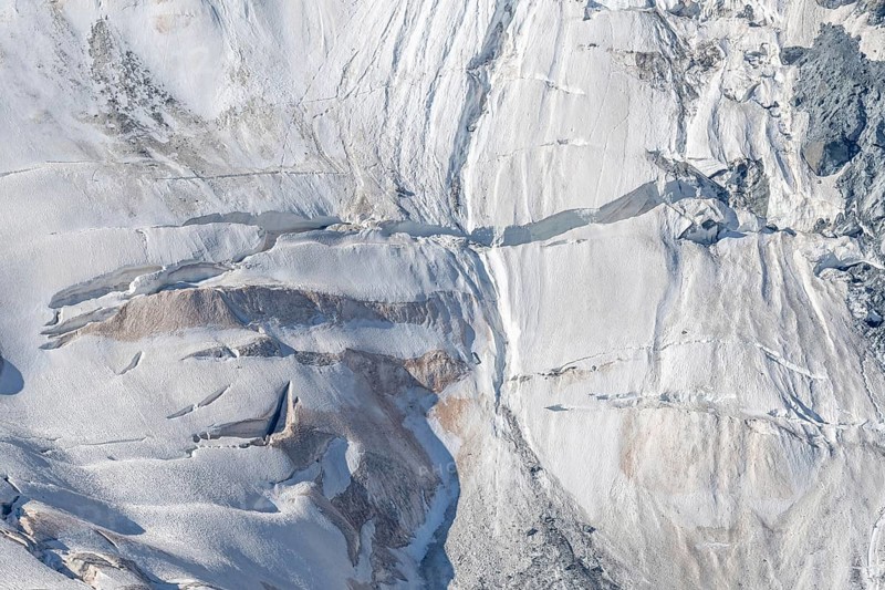 Intricate patterns of ice and rock are showcased in this stunning glacial landscape, revealing the effects of time on the frozen surface. The bright daylight emphasises the textures and colours. Gorner Glacier, Zermatt, Valais, Alps, Swiss