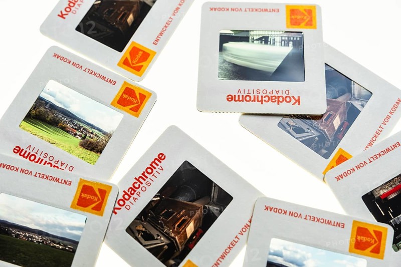 Many framed Kodachrome slides on a light table with magnifying glass, top shot