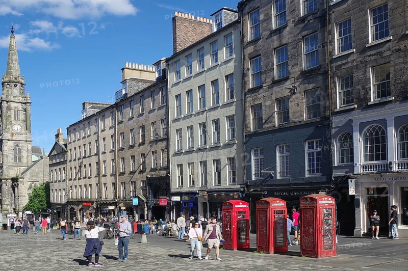 Lively street view with historic buildings and striking red telephone boxes in daylight, Royal Mile, Old Town, Edinburgh, Scotland, United Kingdom
