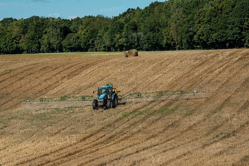 Tractor spreading fertilizer on harvested stubble field in Ystad municipality, Skåne county, Sweden, Scandinavia