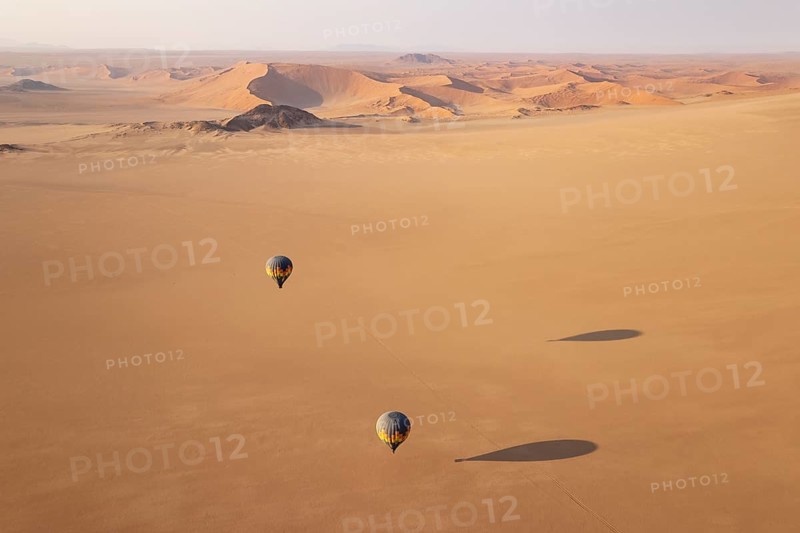 Two hot-air balloons above an arid plain at the edge of the Namib Desert. Aerial view from another balloon. Namibia