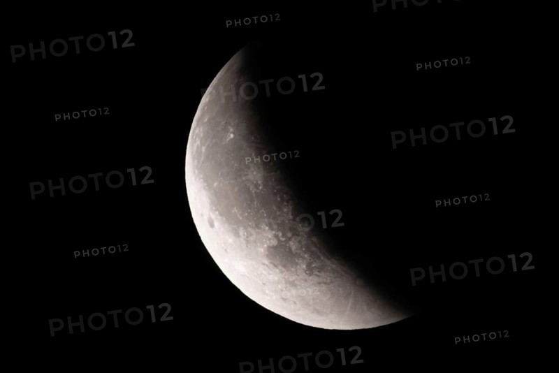 After a total lunar eclipse, the moon appears shortly after its rise in the evening sky as a so-called blood moon in front of it then begins to emerge from the Earth's umbra, Frankfurt am Main, Hesse, Germany