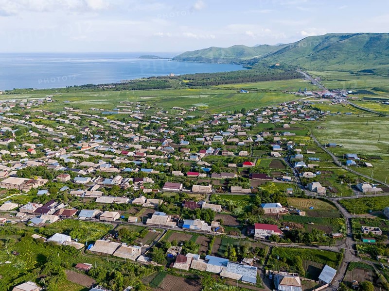 Vast landscape with houses and green fields by the sea and mountains in the distance, aerial view, Tsovagyugh, Lake Sevan, Gegharkunik Province, Armenia