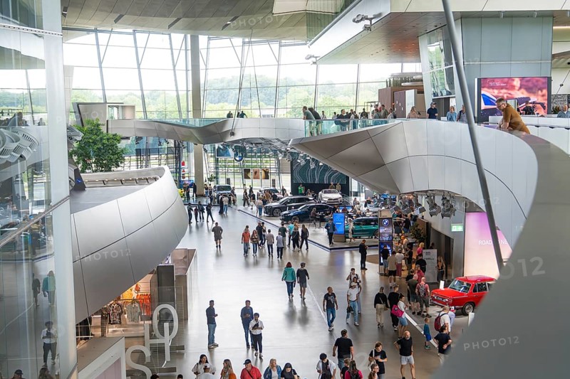 Modern interior with people and exhibited cars in a light-flooded environment, BMW Welt, Munich, Germany