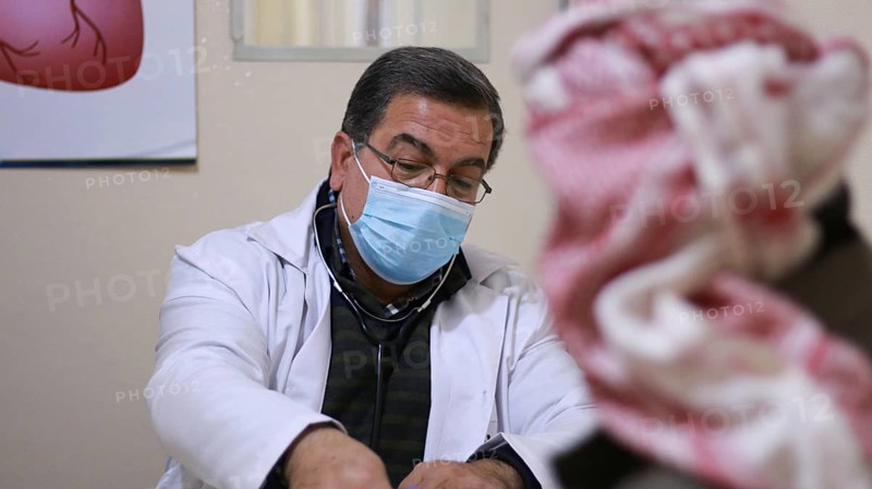 A Syrian doctor wearing a protective mask consults with a displaced patient inside a medical clinic. Aleppo, Syria May 28, 2022, Aleppo, Syria