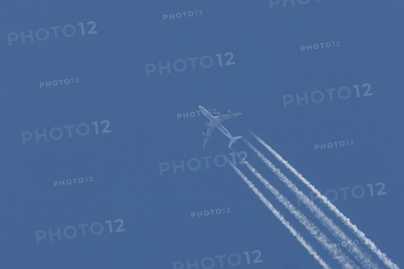 Airbus A340-300 jet aircraft of Lufthansa airlines in flight in a blue sky with vapour trails or contrails behind, England, United Kingdom