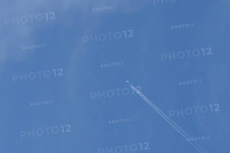 Boeing 737 jet passenger aircraft of Norweign Air with a vapour trial or contrail behind flying in a blue sky, England, United Kingdom
