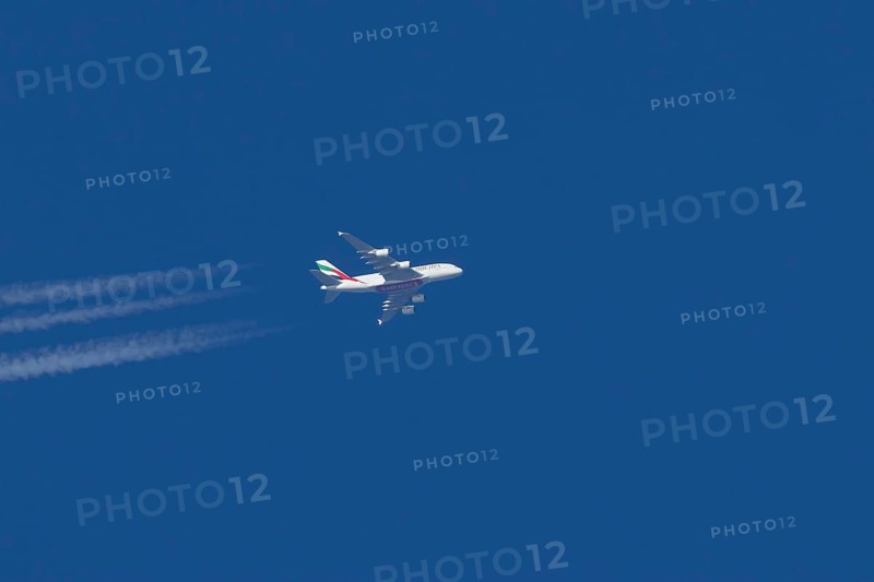 Airbus A380 jet passenger aircraft of Emirates airlines with a vapour trail or contrail flying in a blue sky, England, United Kingdom