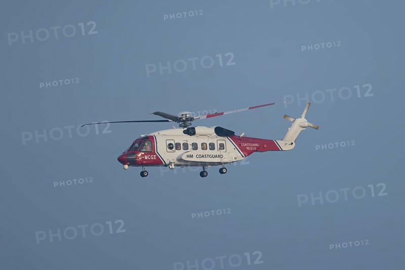 Sikorsky S-92A helicopter of the UK HM Coastguard flying in a blue sky, England, United Kingdom