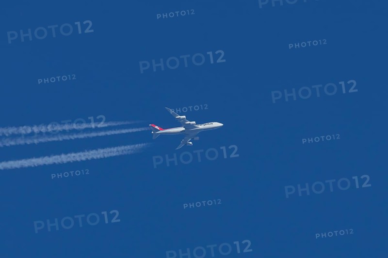 Boeing 747 jumbo jet cargo aircraft of Cargolux airlines with a vapour trail or contrail flying in a blue sky, England, United Kingdom